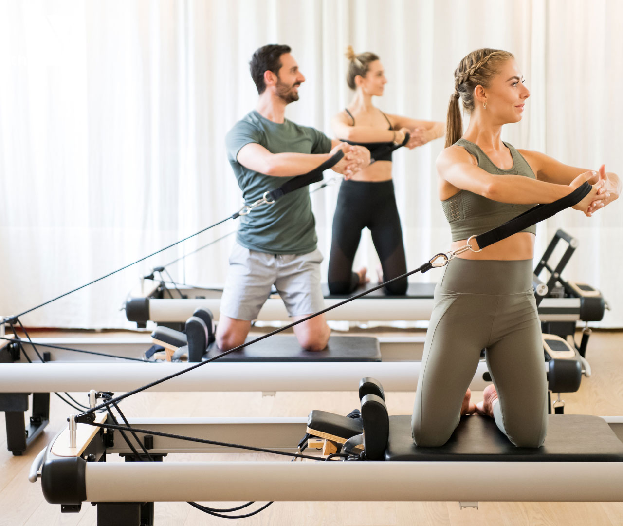 Lezione di Pilates Reformer in gruppo con uomini e donne su macchinari professionali